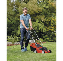 Muž seče trávník elektrickou sekačkou.