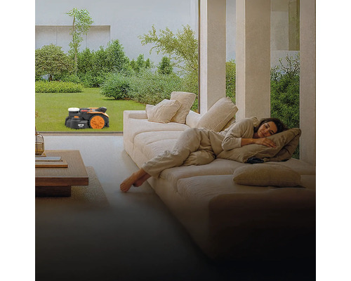 Žena odpočívá na gauči, zatímco robotická sekačka seká trávník