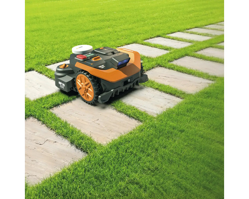 Robotická sekačka na trávníku a cestě z kamenných desek