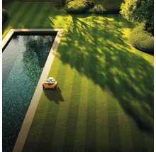 Automatická údržba trávníku v zahradě s robotickou sekačkou vedle bazénu