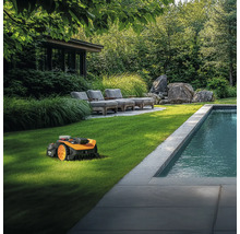Robotická sekačka na trávu na udržovaném trávníku vedle bazénu v zahradě.