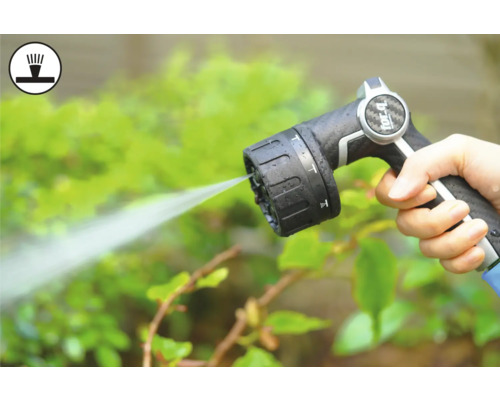 Ruka drží stříkací pistoli zahradní hadice při zalévání rostlin