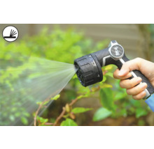 Osoba drží zahradní stříkací pistoli, která stříká vodu