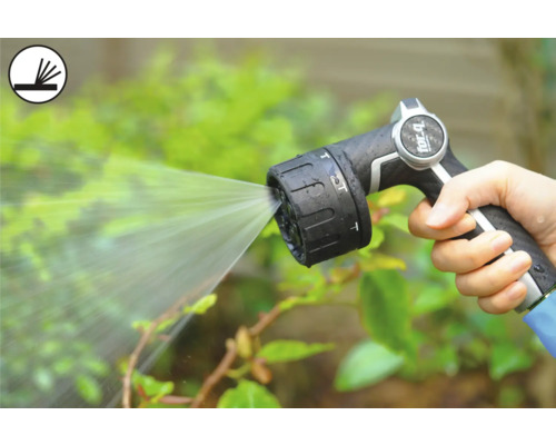 Osoba drží zahradní stříkací pistoli, která stříká vodu