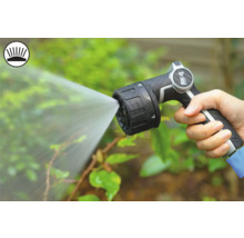 Ruka drží zahradní stříkací pistoli, která stříká vodu