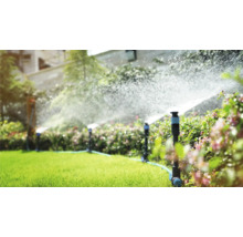 Zavlažovací systém v zahradě s trávníkovými postřikovači v provozu