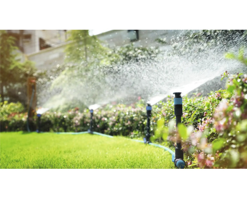 Zavlažovací systém v zahradě s trávníkovými postřikovači v provozu