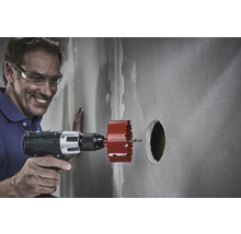 Muž vrtá otvor do zdi pomocí děrovky