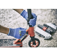 Osoba opravuje koloběžku pomocí nářadí a ochranných rukavic