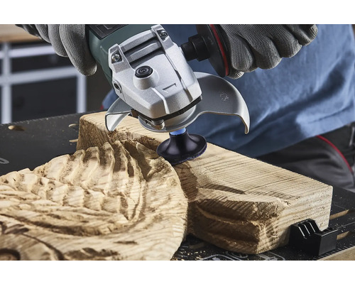 Osoba používá úhlovou brusku k opracování dřeva.