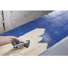 Osoba používá rozmetadlo barev k nanášení barvy na dřevo