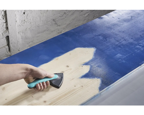 Osoba používá rozmetadlo barev k nanášení barvy na dřevo