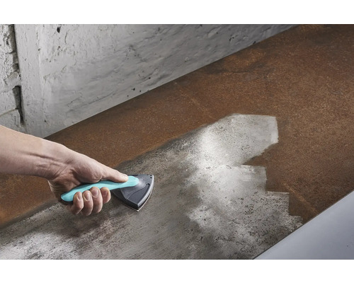 Ruka s trojúhelníkovou škrabkou čistící kovový povrch