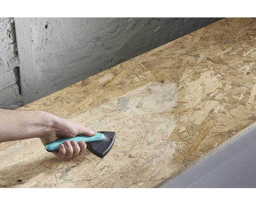 Ruka drží brusný blok a brousí dřevěnou desku.