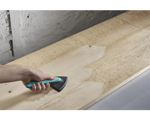 Ruka brousí dřevěnou desku trojúhelníkovou bruskou