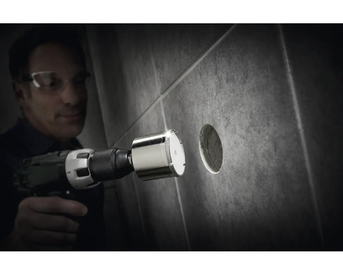 Muž vrtá diamantovou korunkou otvor do dlaždice.