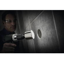 Muž vrtá diamantovou korunkou otvor do dlaždice.