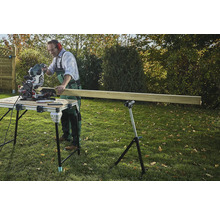 Řemeslník řeže dřevo pokosovou pilou na řezacím stole na zahradě.