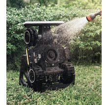 Zavlažovaný zahradní robot s pásovým pohonem v provozu na trávníku.