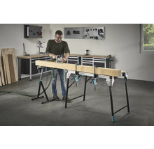 Muž frézuje dřevo na pracovním stole se šroubovými svorkami v dílně