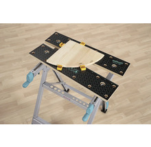 Pracovní stůl Wolfcraft Master 200 s kusem dřeva a upínacími čelistmi.