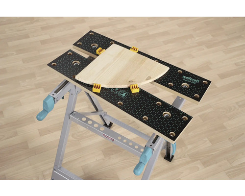 Pracovní stůl Wolfcraft Master 200 s kusem dřeva a upínacími čelistmi.