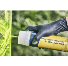 Osoba v rukavicích používá značkovací sprej pro stavebnictví a lesnictví.