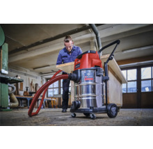 Dílna s mokro-suchým vysavačem Einhell a mužem opracovávajícím dřevěnou desku