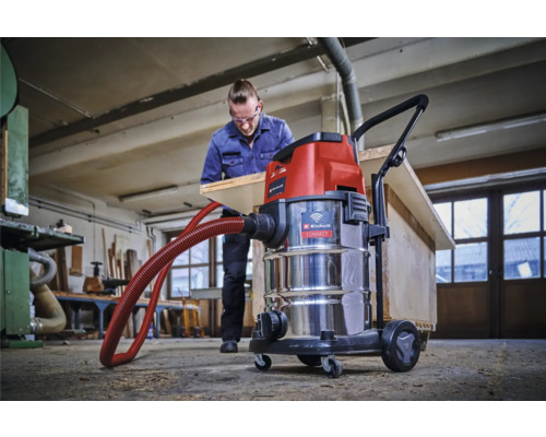 Dílna s mokro-suchým vysavačem Einhell a mužem opracovávajícím dřevěnou desku