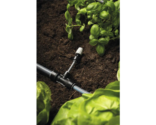 Zavlažovací systém s T-kusem a rostlinami v zahradním záhonu