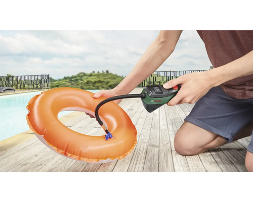 Osoba nafukuje plavecký kruh pomocí vzduchové pumpy Bosch vedle bazénu.