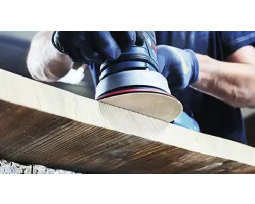 Osoba brousí dřevěnou desku excentrickou bruskou.