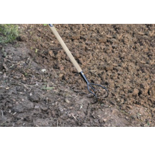 Trojzubá zahradní motyka s dřevěnou rukojetí v zahradní půdě