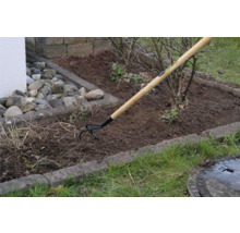 Zahradní scéna s kypřičem se dřevěnou rukojetí při zpracování půdy