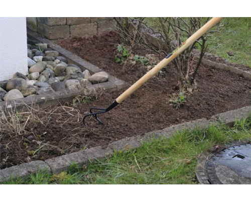 Zahradní scéna s kypřičem se dřevěnou rukojetí při zpracování půdy