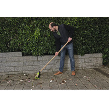 Osoba zametá listí pouličním koštětem.