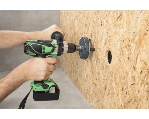 Osoba vrtá otvor do dřevěné desky pomocí akumulátorového vrtacího šroubováku.