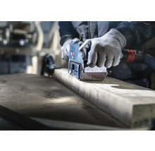 Řemeslník brousí dřevo pásovou bruskou