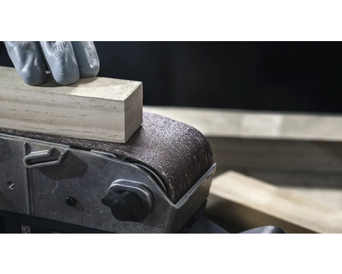 Detail pásové brusky brousí kus dřeva