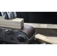 Detail pásové brusky brousí kus dřeva