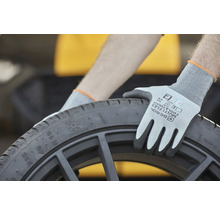 Osoba s ochrannými rukavicemi drží černou pneumatiku.