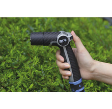 Zahradní stříkací pistole v ruce před keři