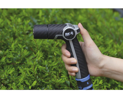 Zahradní stříkací pistole v ruce před keři