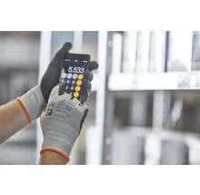 Osoba v pracovních rukavicích používá kalkulačku na smartphonu.