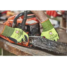 Osoba obsluhující řetězovou pilu s ochrannými rukavicemi.