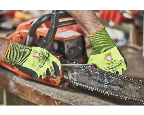 Osoba obsluhující řetězovou pilu s ochrannými rukavicemi.
