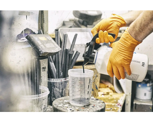 Osoba v rukavicích nalévá barvu do odměrky