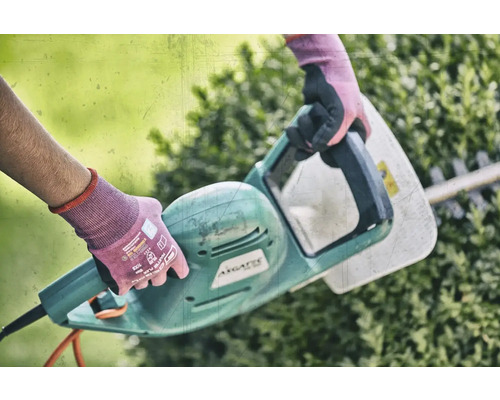 Osoba používá elektrické nůžky na živý plot k úpravě živého plotu.