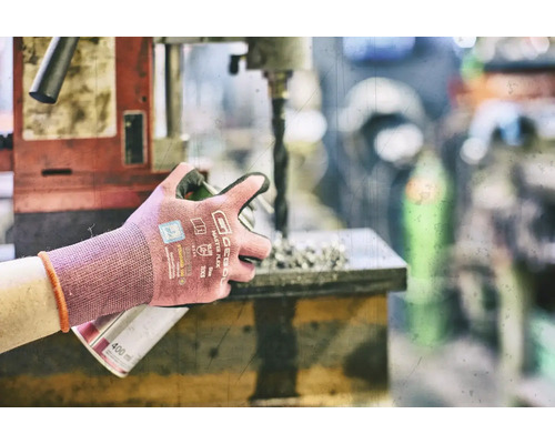 Osoba pracuje s vrtačkou a nosí pracovní rukavice pro ochranu.