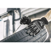 Osoba v pracovních rukavicích drží pneumatiku.